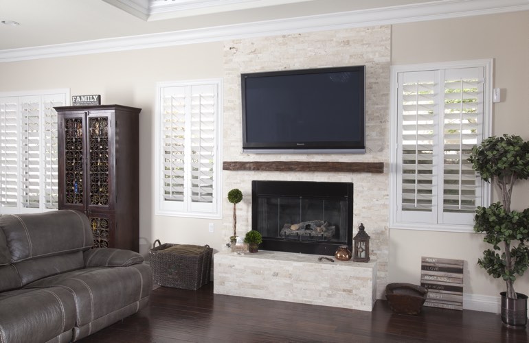White plantation shutters in a Southern California living room with dark hardwood floors.